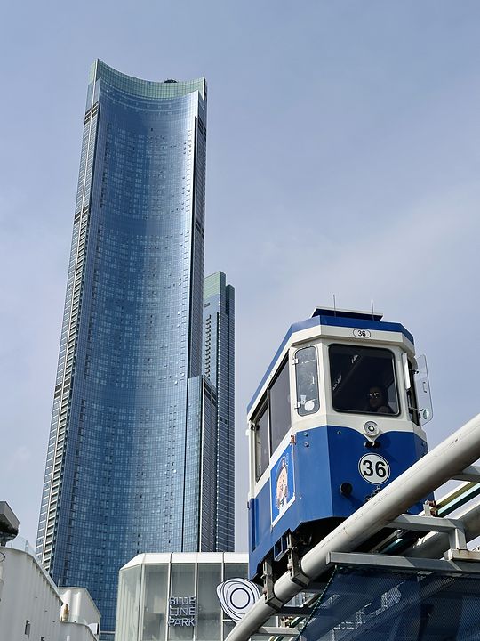 A Blue Line Park carriage on its elevated track in Haeundae, Busan, below a curved glass skyscraper